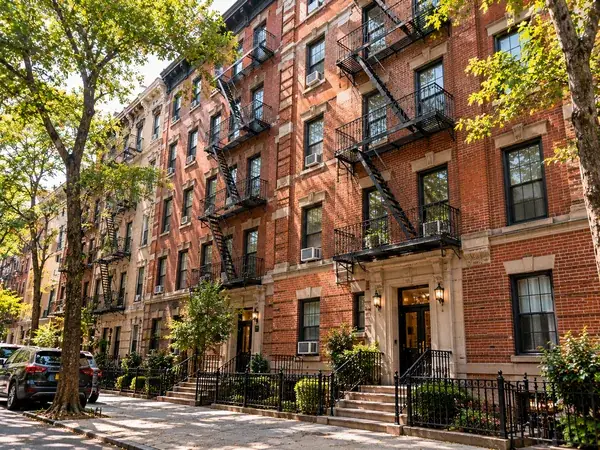 Red brick multifamily building with fire escapes (illustrative image)